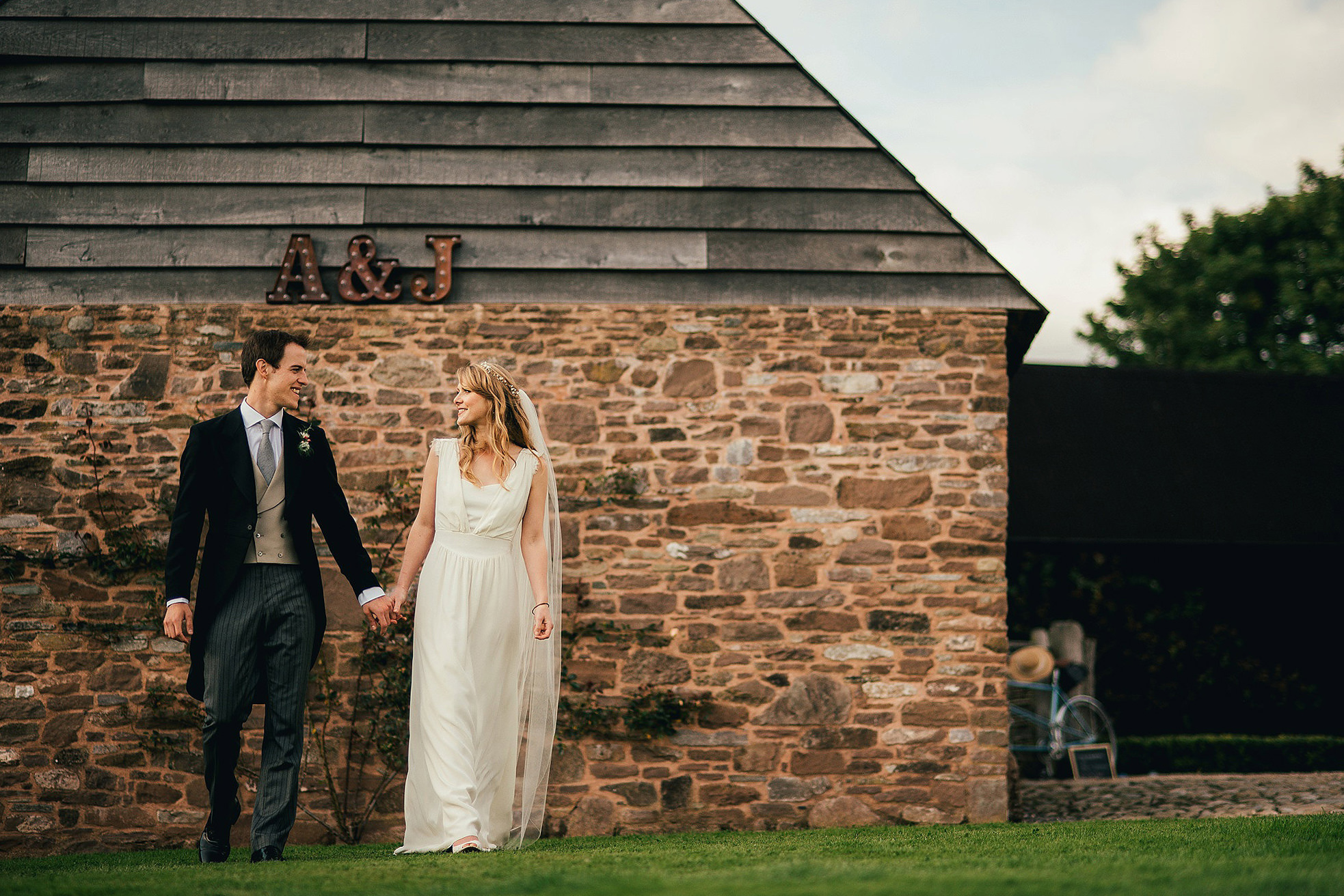 bride and groom walking by rustic barn